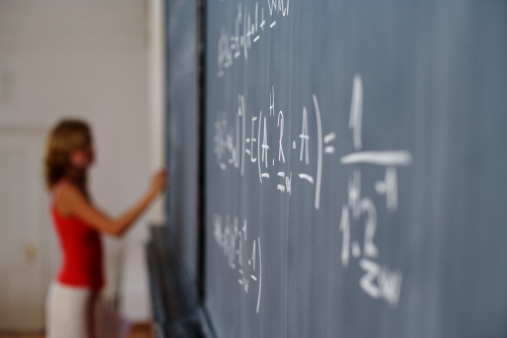 Woman writing arithmetic's on a blackboard, selective focus